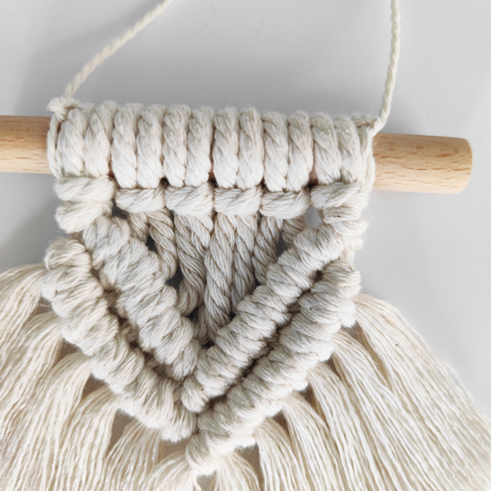 Macrame wall hanging with wooden rod on a light gray background